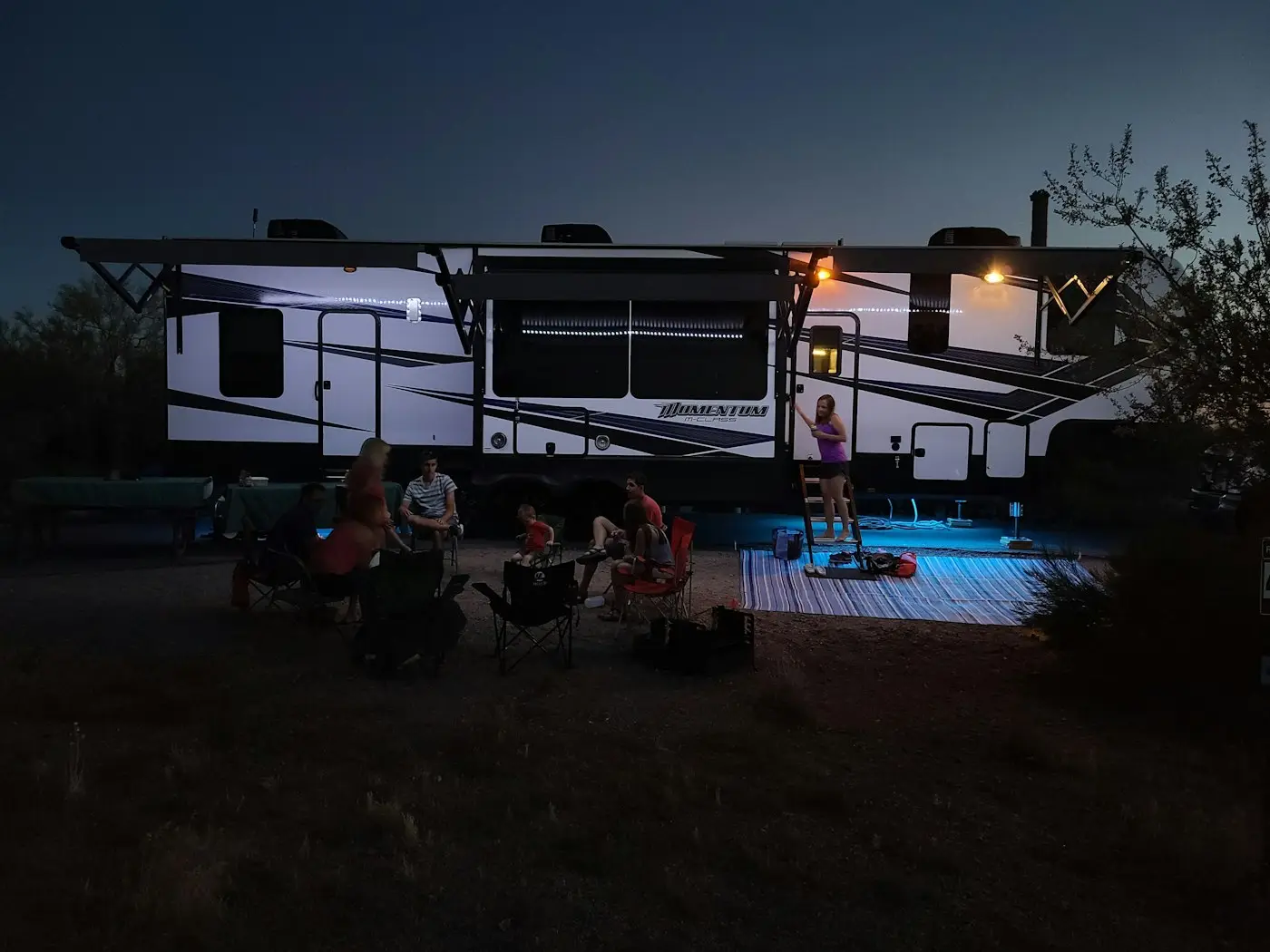 A family gathered outside their RV at dusk
